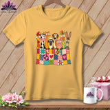 A gold short-sleeved t-shirt features a colorful graphic of cartoon farm animals peeking over a patchwork quilt.