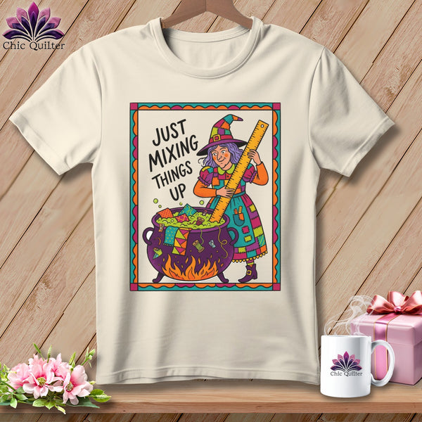 T-shirt with cartoon witch stirring cauldron with ruler, text "JUST MIXING THINGS UP".