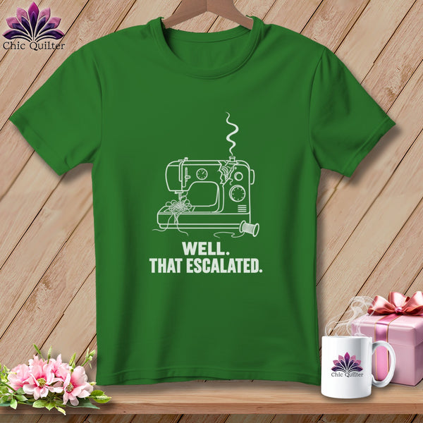 Green t-shirt with white outline of a broken sewing machine and text "WELL. THAT ESCALATED."