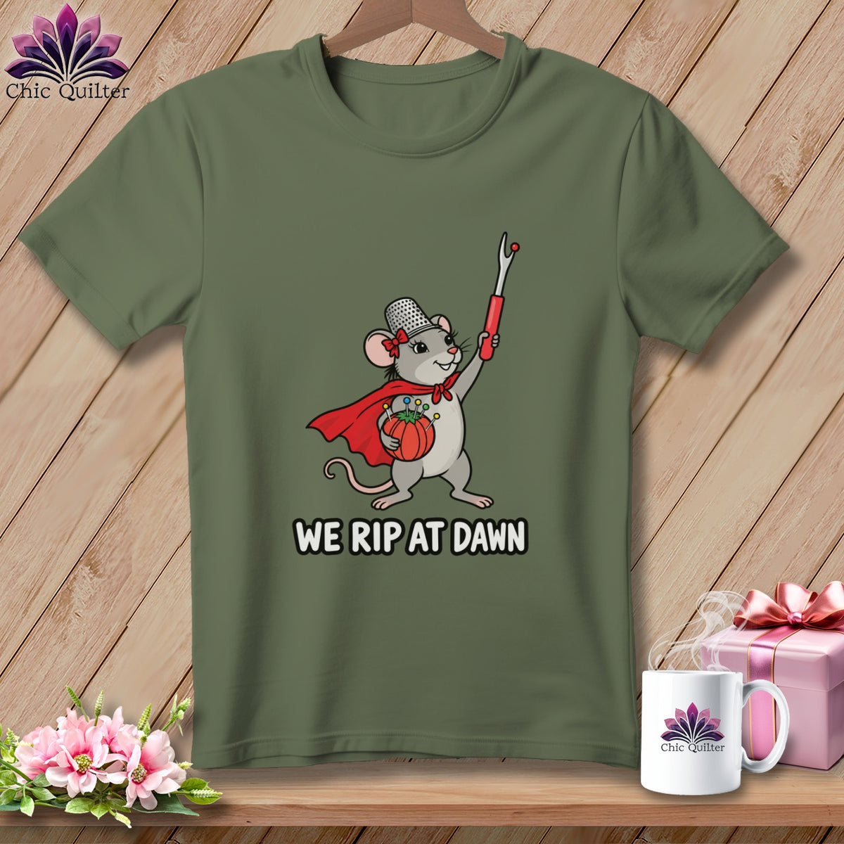 Olive green t-shirt featuring a superhero mouse holding a seam ripper with the text "WE RIP AT DAWN".