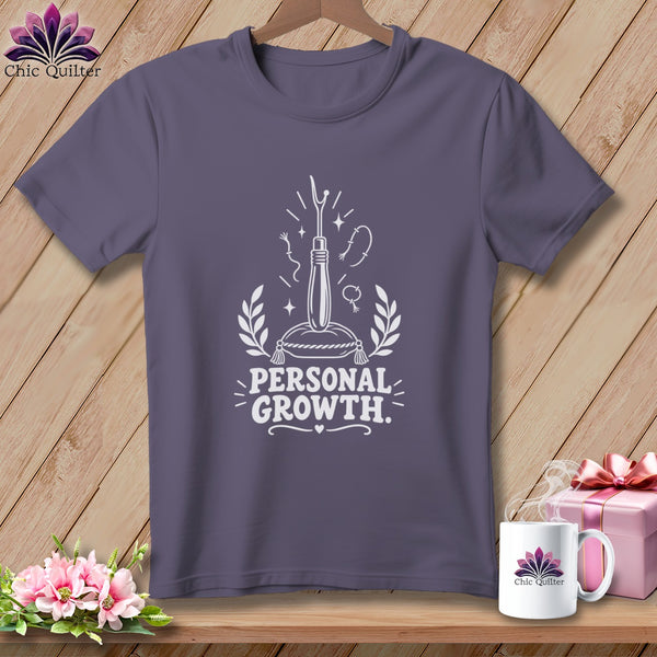 Purple t-shirt with white graphic of a seam ripper and text "PERSONAL GROWTH."