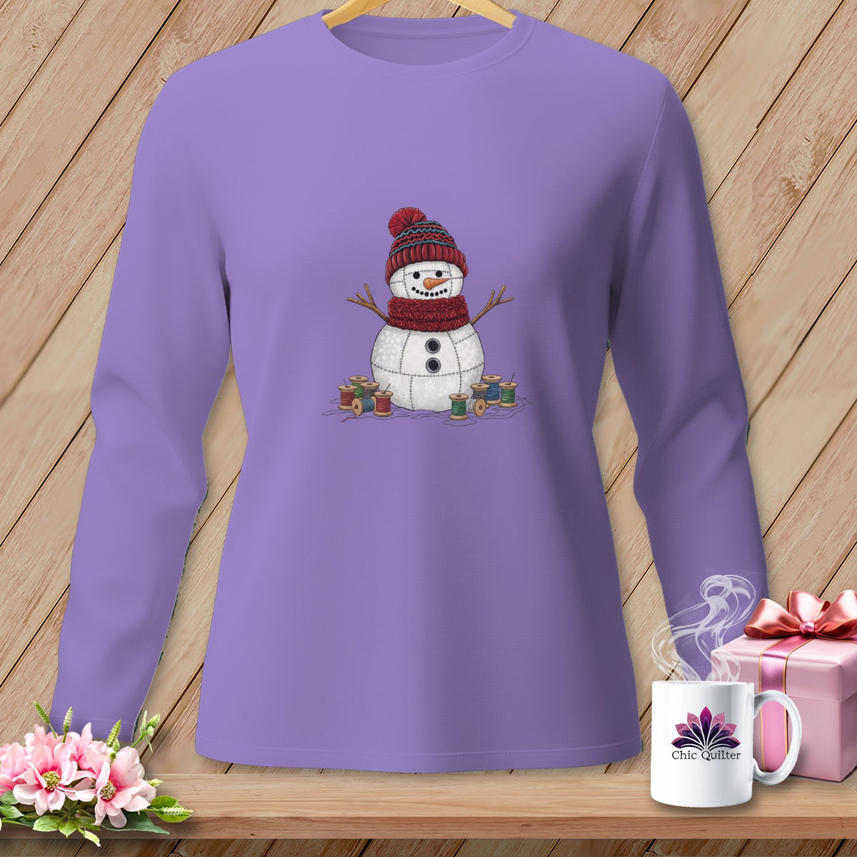 Lavender long-sleeve shirt with a stitched snowman graphic, spools of thread, and "Chic Quilter" mug.