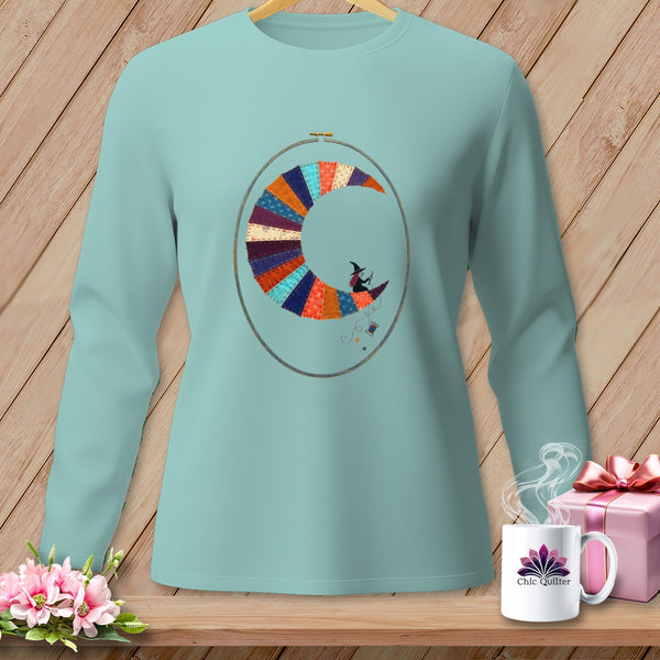 Teal long-sleeve shirt with witch on crescent moon quilt design in embroidery hoop.