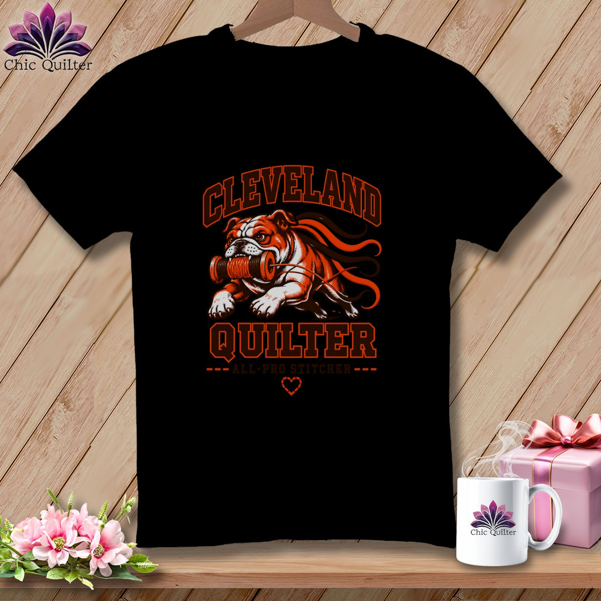 Black t-shirt featuring an orange and white graphic of a bulldog holding a spool of thread and the text Cleveland Quilter.