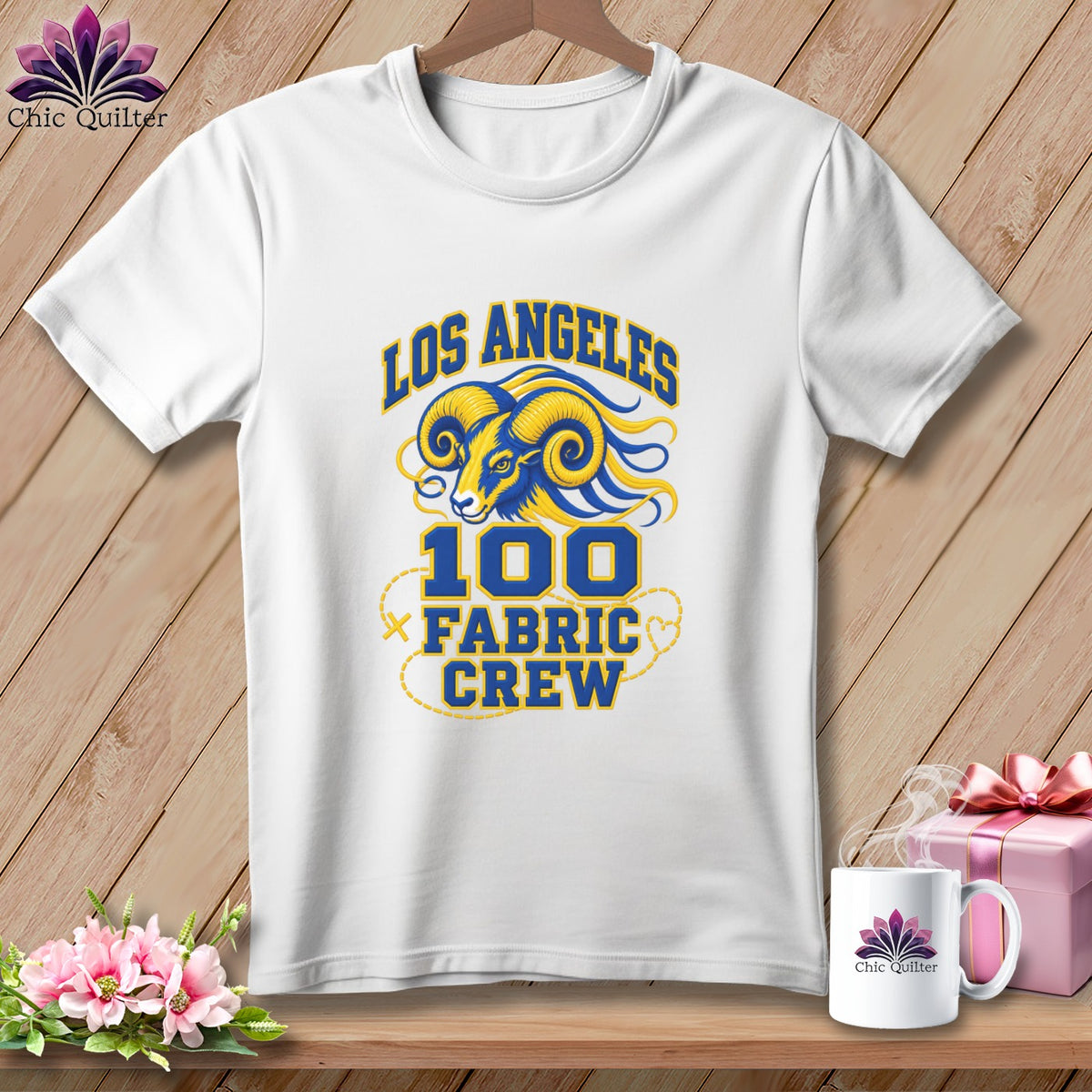 White short-sleeve t-shirt with blue and yellow Los Angeles 100 Fabric Crew graphic on wooden background.