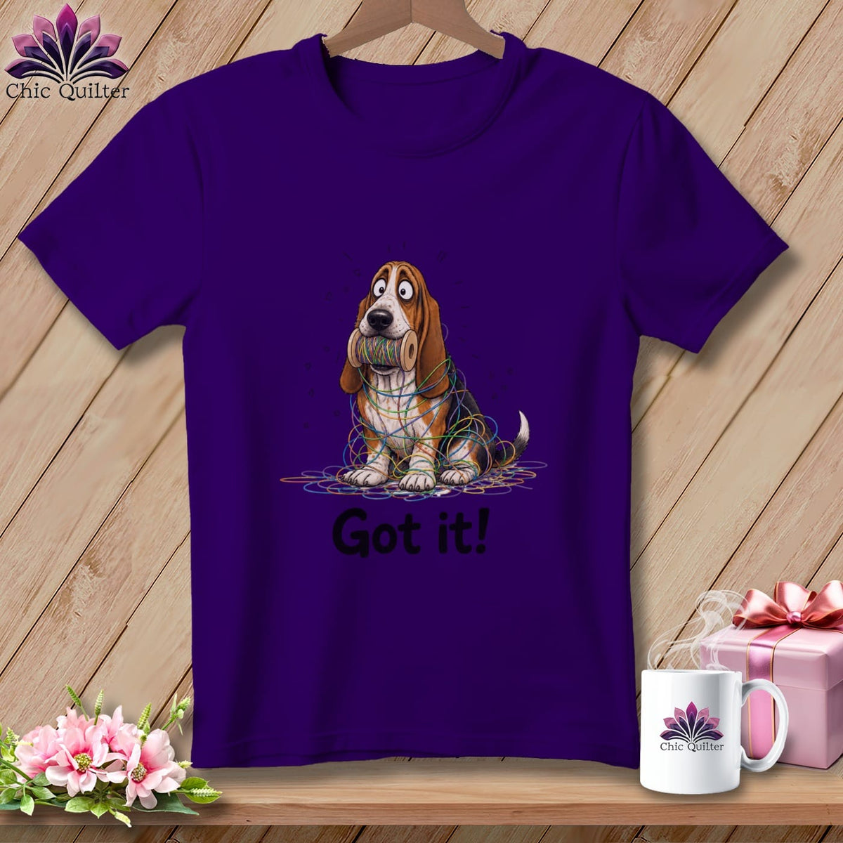 Purple t-shirt with cartoon basset hound tangled in colorful yarn, "Got it!" text.
