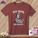 Maroon t-shirt featuring a graphic of an otter sewing a rabbit into a quilt, with text reading TUCK AROUND AND FIND OUT.
