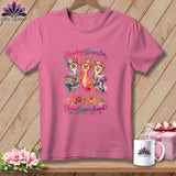 Pink t-shirt with a graphic of three cute birds wearing glasses and flower crowns, holding quilting supplies.