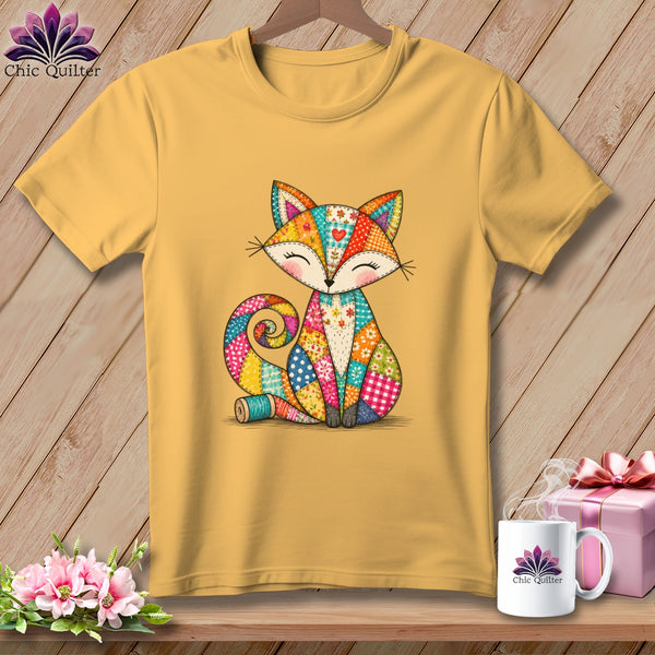 Mustard yellow t-shirt featuring a colorful patchwork fox graphic hanging on a wooden background.