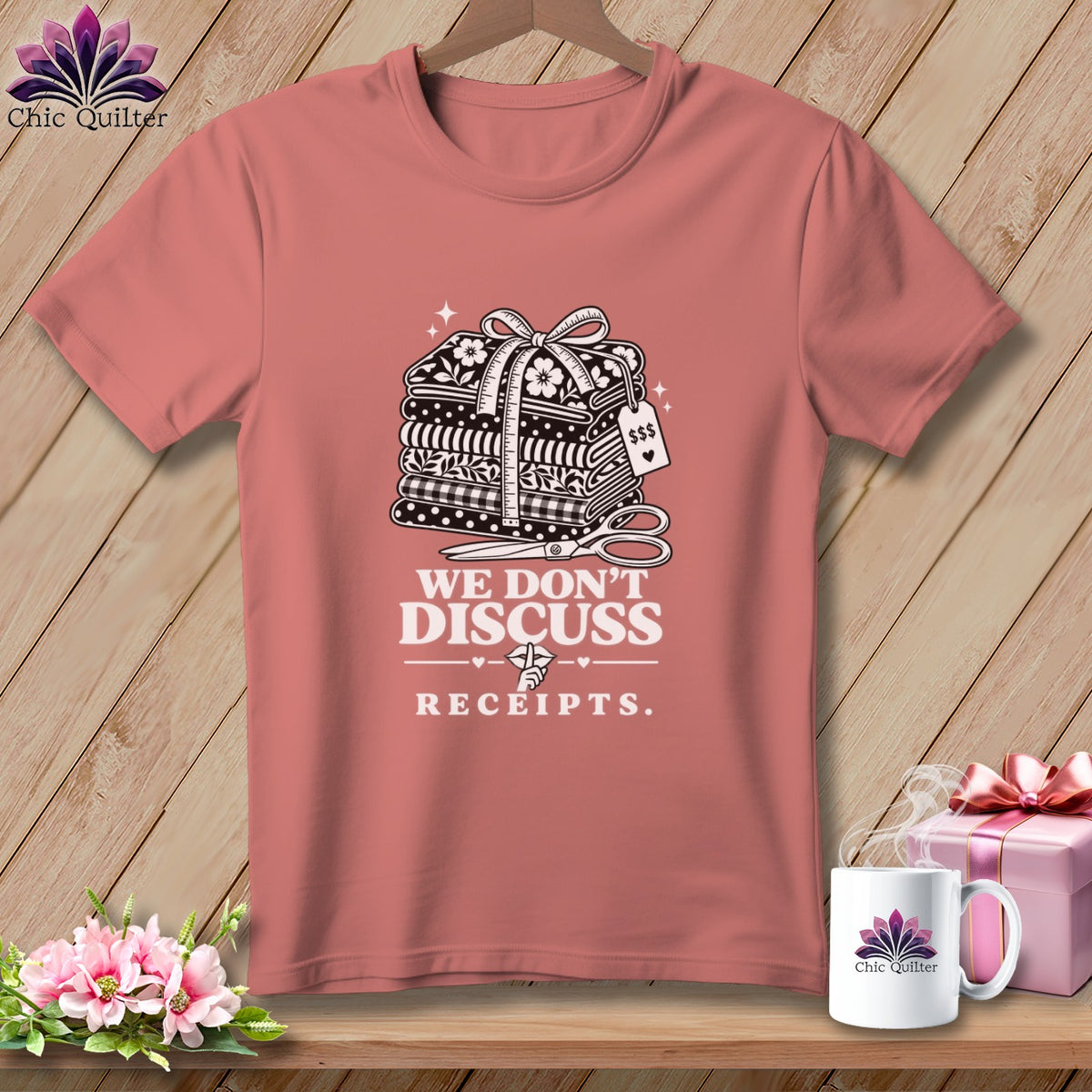 T-shirt with a graphic featuring a stack of fabric, scissors, and text "We Don't Discuss Receipts."