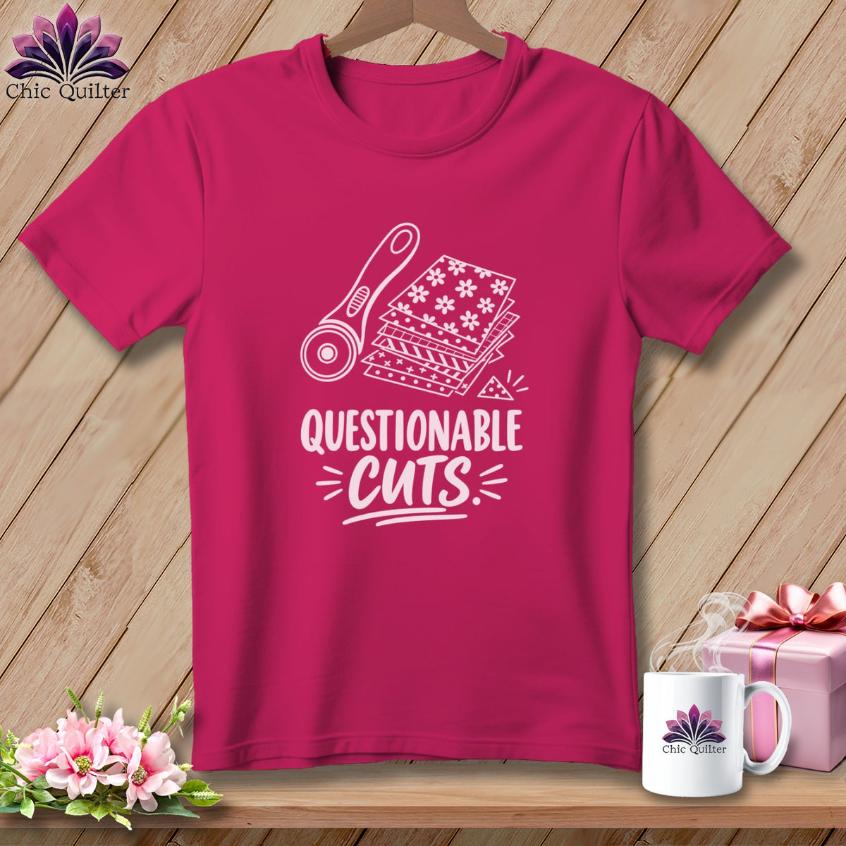Pink t-shirt with graphic of rotary cutter and fabric stacks, text reads "QUESTIONABLE CUTS".