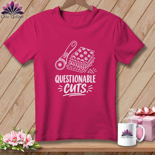 Pink t-shirt with graphic of rotary cutter and fabric stacks, text reads "QUESTIONABLE CUTS".