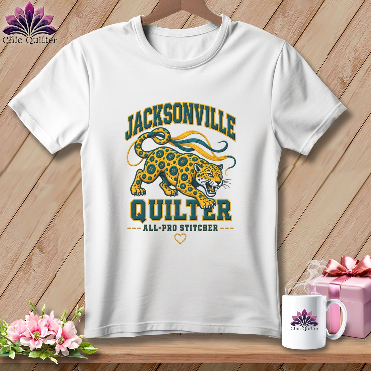 A white t-shirt hanging on a wooden background, featuring a Jacksonville Quilter graphic with a jaguar illustration.