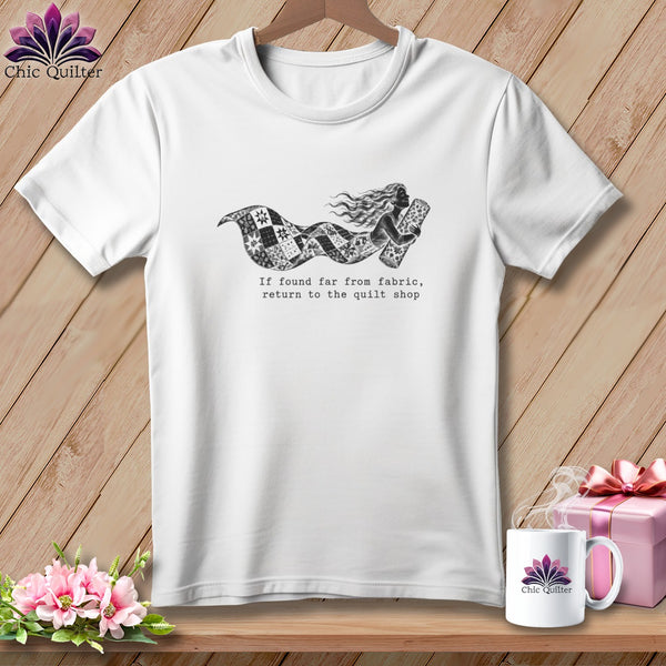 White t-shirt with a mermaid illustration holding fabric and text "If found far from fabric, return to the quilt shop".