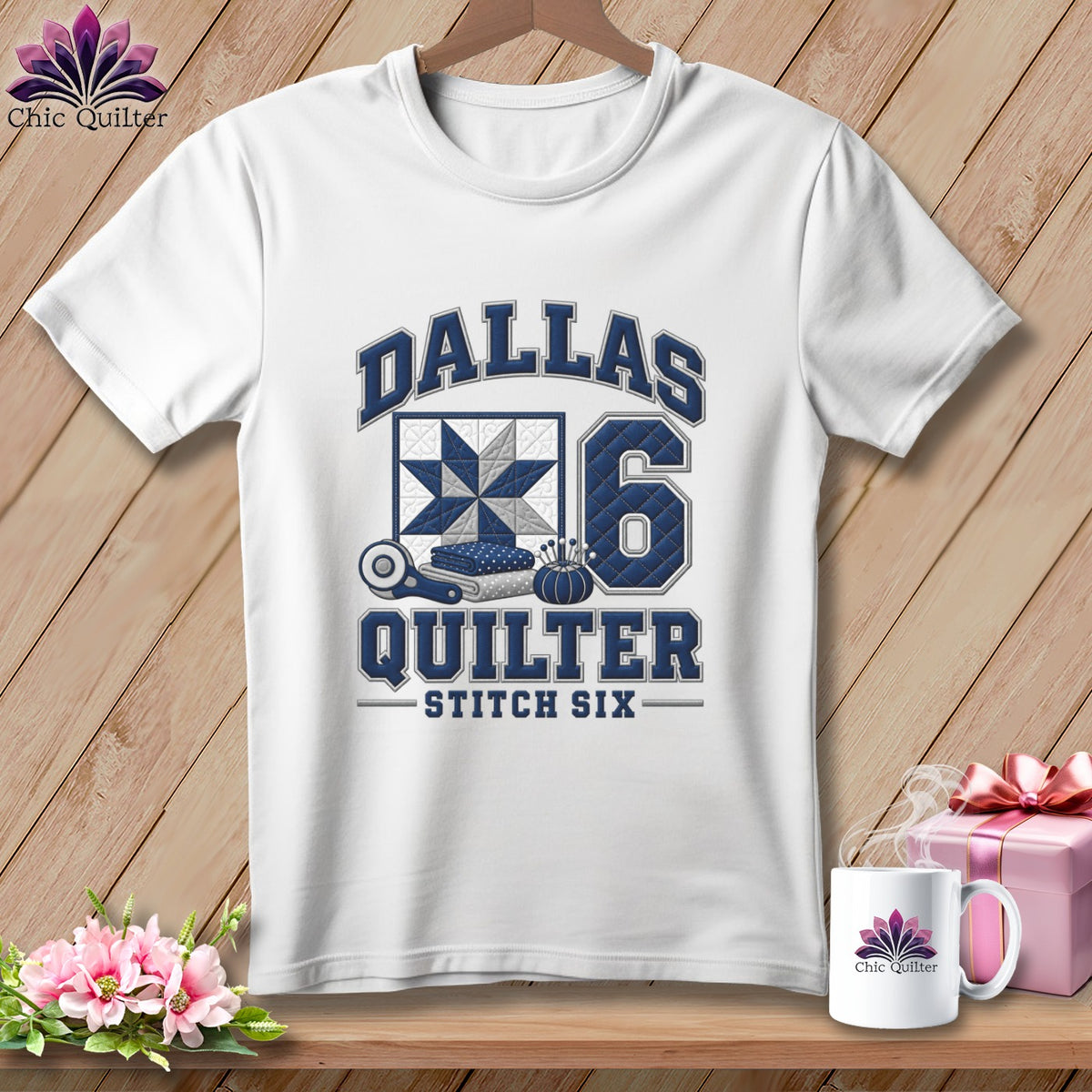 A white t-shirt hanging against a wooden background features blue text reading "DALLAS QUILTER STITCH SIX" alongside a quilted block graphic and the number 6.