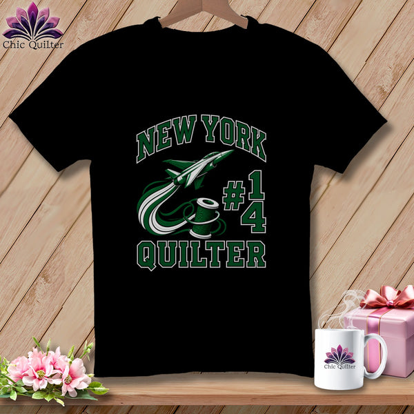 Black t-shirt featuring green and white text that reads New York Quilter, a spool of thread, a jet plane, and the number 14.