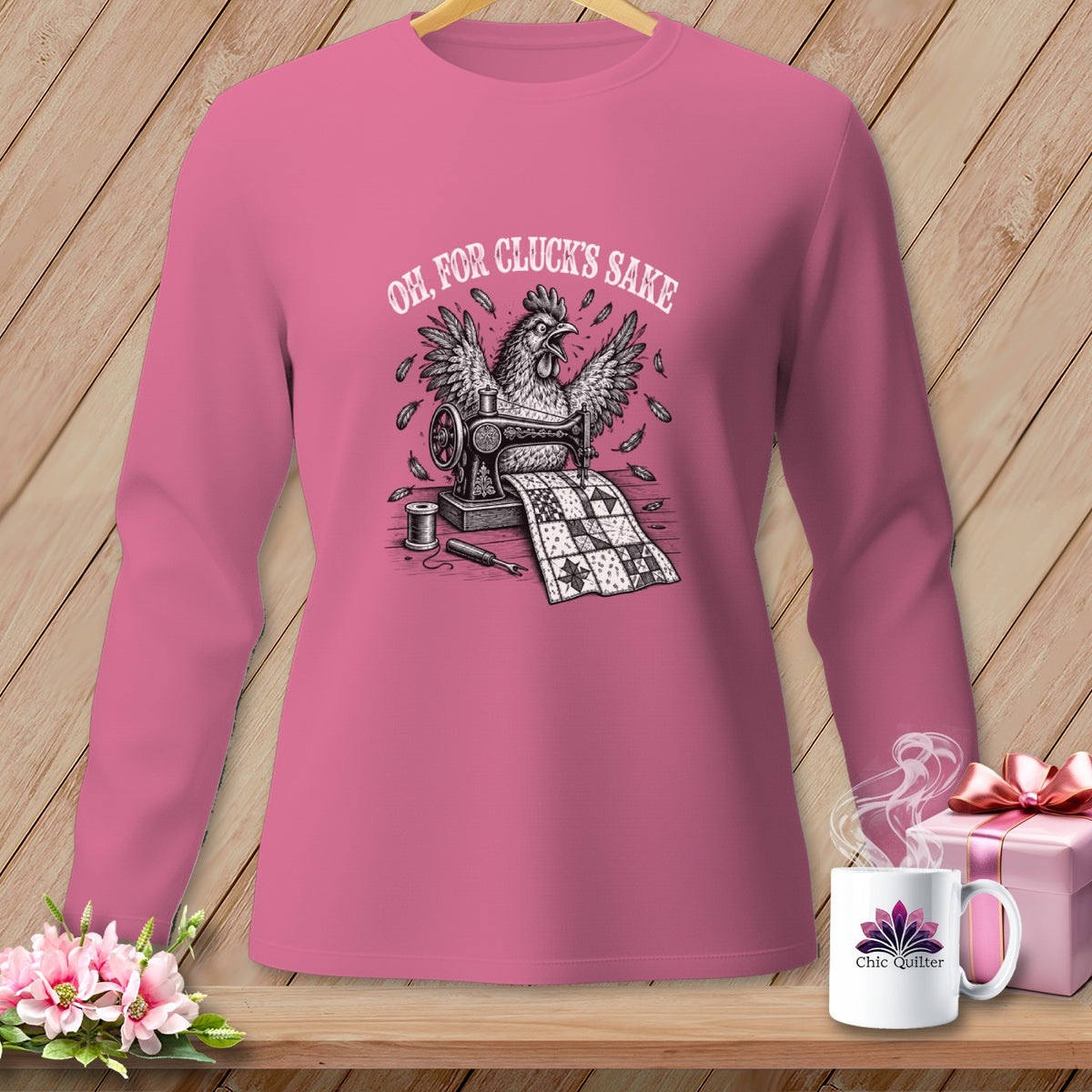 Pink long-sleeved shirt with a chicken sewing a quilt, text "Oh, for cluck's sake".