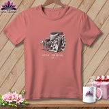 Pink t-shirt with sketch of armchair, quilt, and mug with text 
