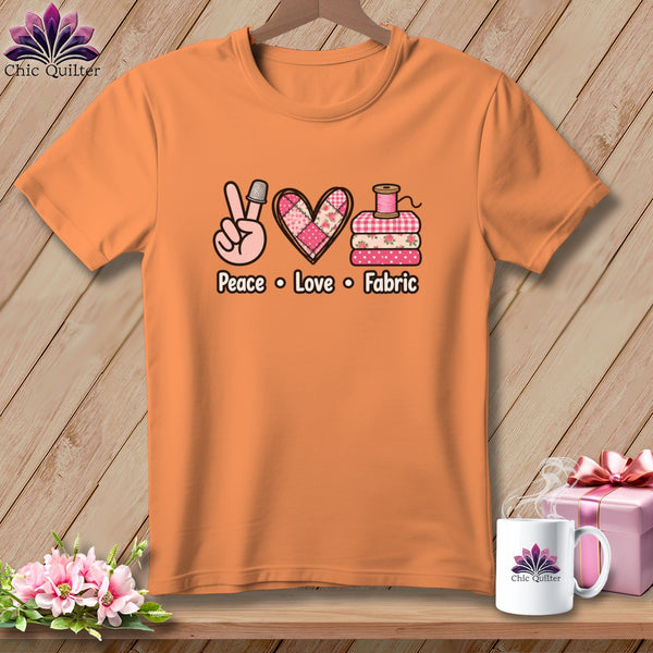 Orange t-shirt featuring a peace sign, heart, stacked fabric, and the text Peace Love Fabric.