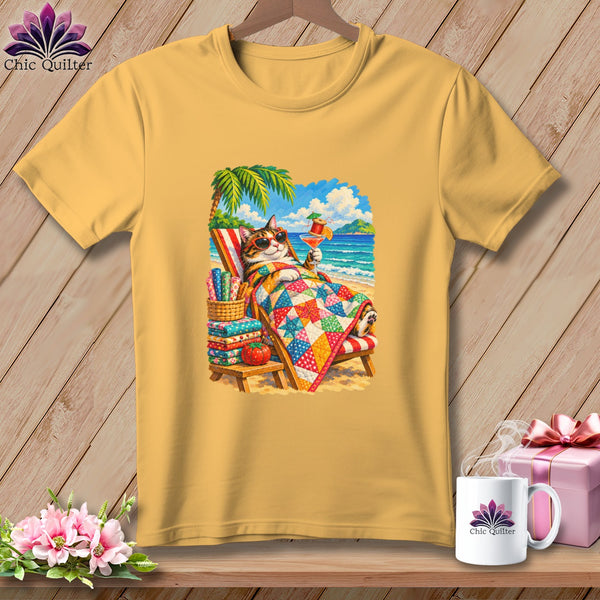 Gold t-shirt featuring a graphic of a cat in sunglasses relaxing on a beach lounge chair under a quilt.
