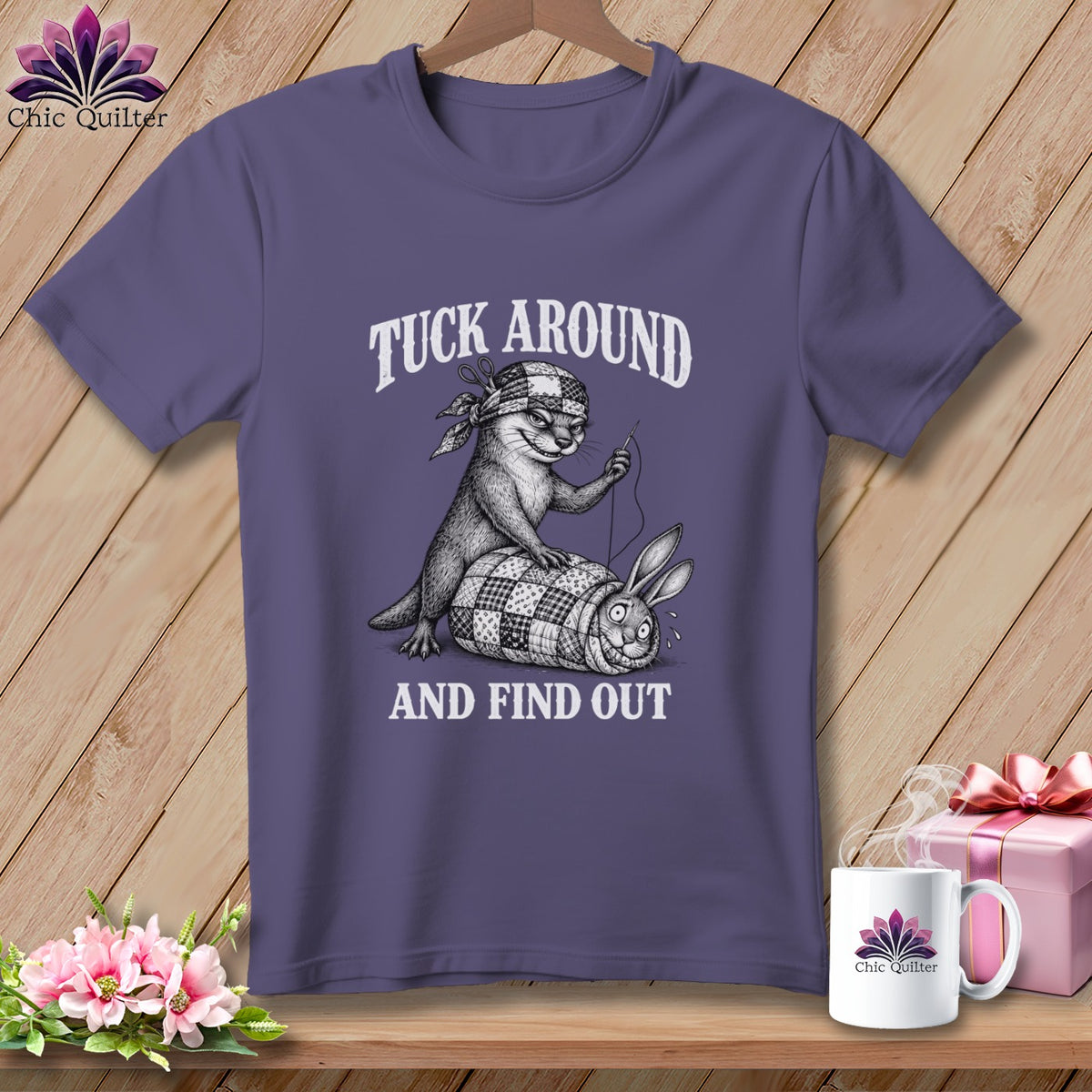 Purple t-shirt featuring an illustration of an otter sewing a rabbit into a quilt, with text reading TUCK AROUND AND FIND OUT.