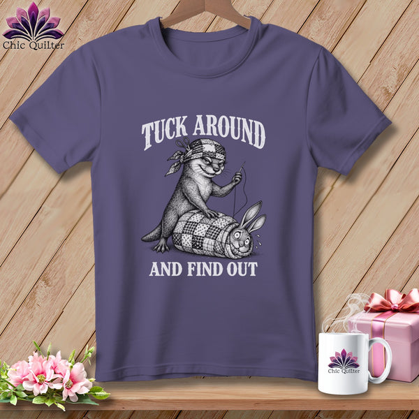 Purple t-shirt featuring an illustration of an otter sewing a rabbit into a quilt, with text reading TUCK AROUND AND FIND OUT.