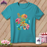 Teal t-shirt featuring a colorful patchwork hibiscus flower graphic on a wooden background with accessories.