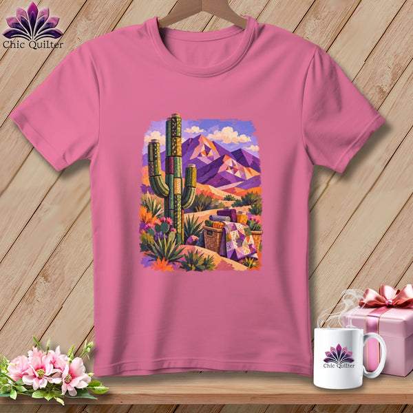 A pink crewneck t-shirt featuring a colorful desert landscape graphic with cacti and mountains.