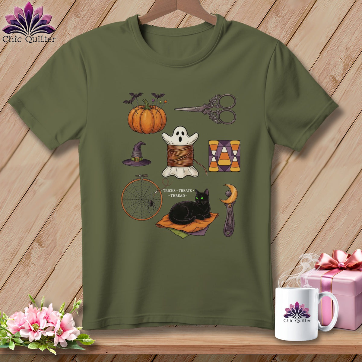 Olive green t-shirt with Halloween-themed sewing icons including a pumpkin, ghost, needle, thread, scissors, and cat.
