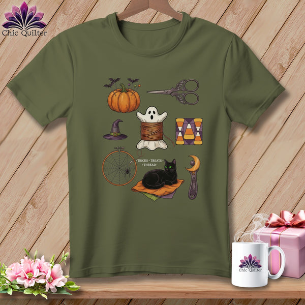 Olive green t-shirt with Halloween-themed sewing icons including a pumpkin, ghost, needle, thread, scissors, and cat.