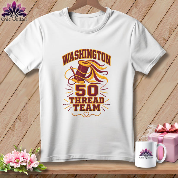 White short-sleeved t-shirt hanging on a wooden background, featuring graphic text reading WASHINGTON 50 THREAD TEAM.