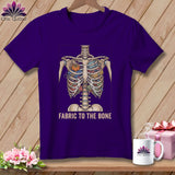 Purple t-shirt featuring a skeleton chest filled with fabric and sewing notions.