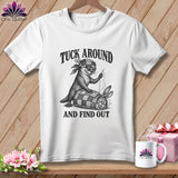 A white t-shirt featuring a black graphic of an otter sewing a rabbit into a quilt, with text reading 