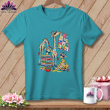 Teal crewneck t-shirt featuring a colorful graphic of giraffes sewing and stacking vibrant quilts.