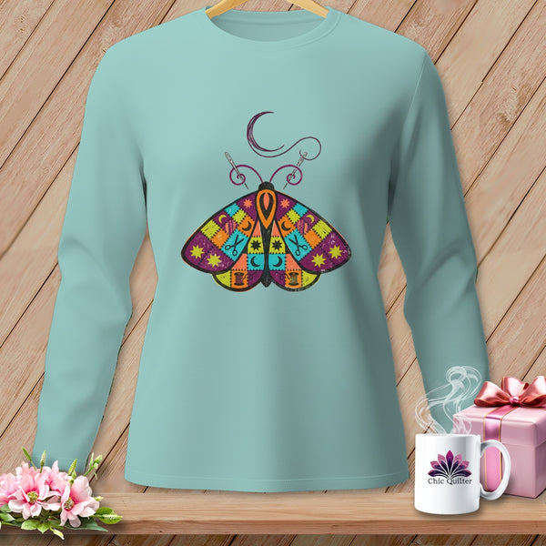 Light blue long-sleeve shirt with a colorful patchwork moth and sewing needle design.