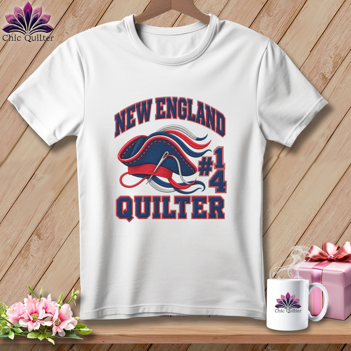 White crewneck t-shirt with a blue, red, and white "New England Quilter" embroidery design.