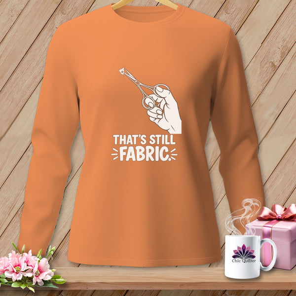 Orange long-sleeve shirt with scissors cutting fabric and text "THAT'S STILL FABRIC".