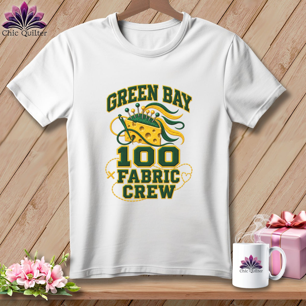 A white t-shirt features Green Bay Fabric Crew text and a graphic of a cheese wedge pincushion.
