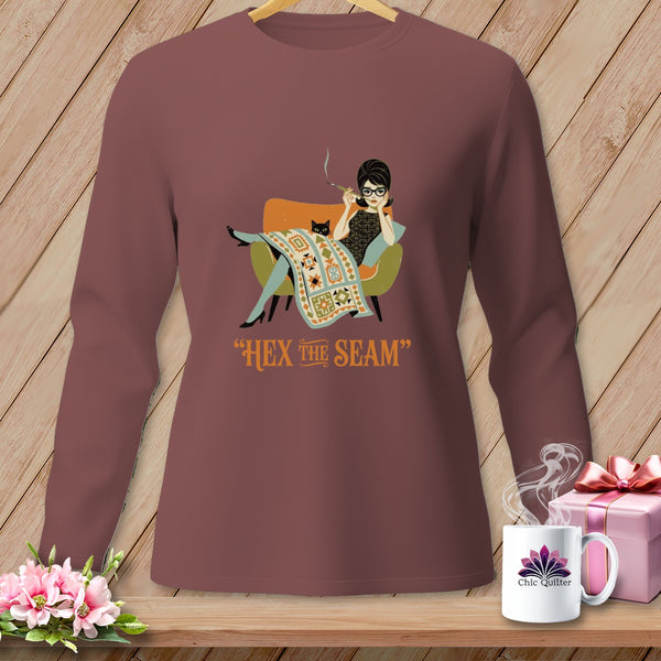 Brown long-sleeve shirt with a graphic of a woman and cat sewing a quilt, and the text "HEX THE SEAM".