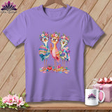 A light purple t-shirt displays a graphic of three colorful birds wearing glasses and flower crowns.