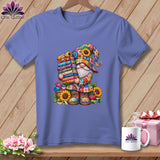 Periwinkle blue t-shirt featuring a colorful floral gnome holding a stack of fabric rolls.