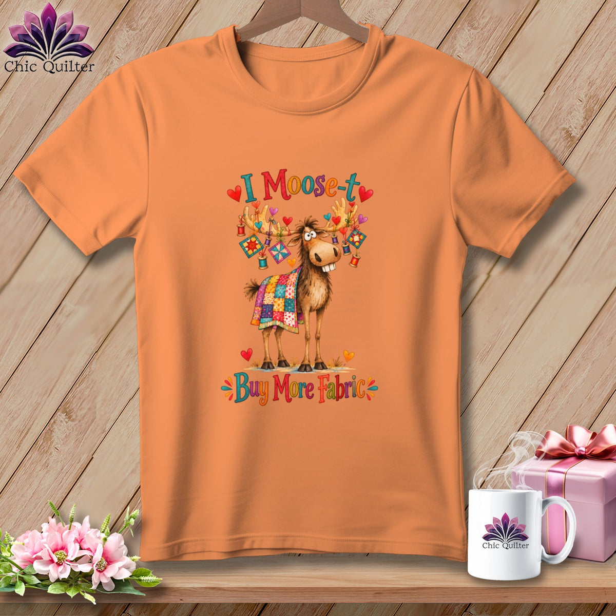 Orange t-shirt featuring a moose wearing a quilt and the text I Moose-t Buy More Fabric.