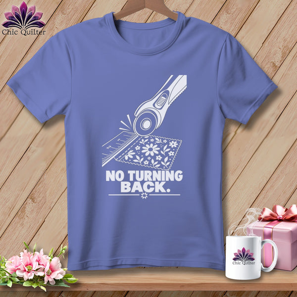 Purple t-shirt with white graphic of rotary cutter, ruler, fabric, and text "NO TURNING BACK."