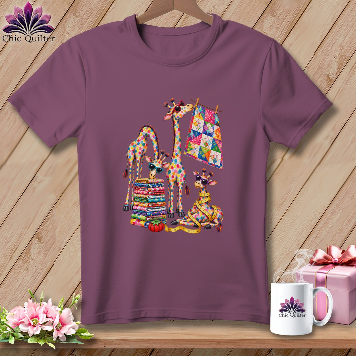 A purple t-shirt hangs on a wooden hanger, featuring a colorful graphic of giraffes with quilting supplies.