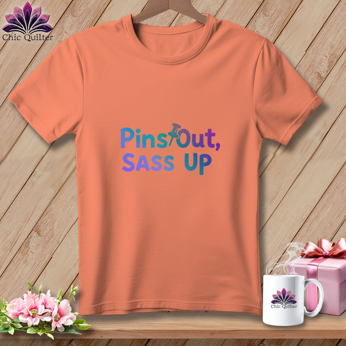 Orange t-shirt with gradient text "Pins Out, SASS UP" and a pushpin icon.