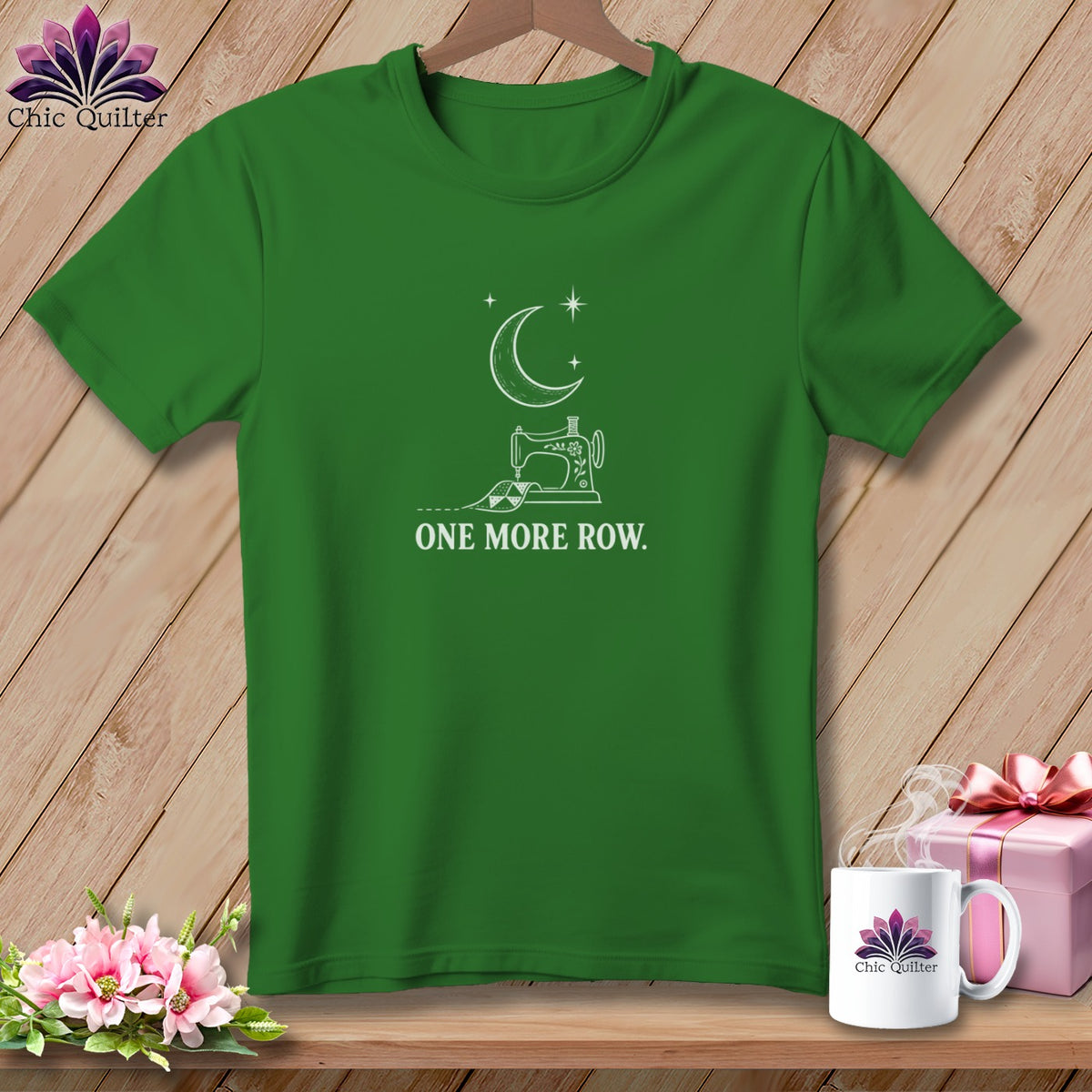 Green t-shirt with white line art of a sewing machine, moon, stars, and text "ONE MORE ROW."