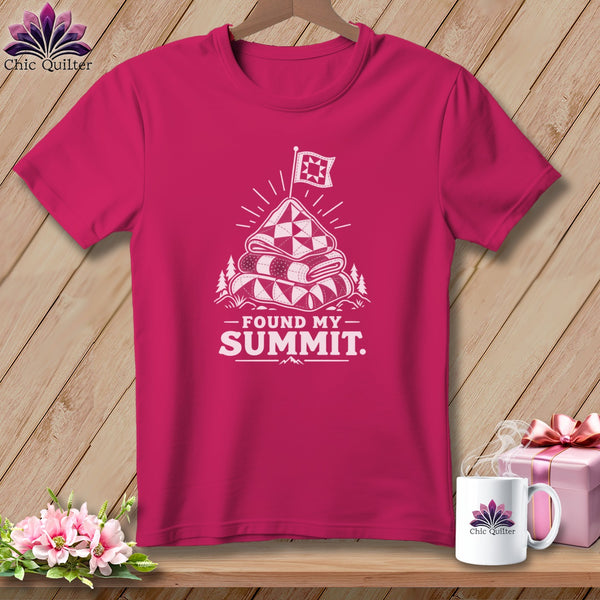Pink t-shirt with a graphic of stacked quilts topped by a flag and the text "Found My Summit."