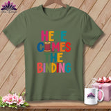 Olive green crewneck t-shirt featuring the colorful text Here Comes the Binding and a spool of pink thread.