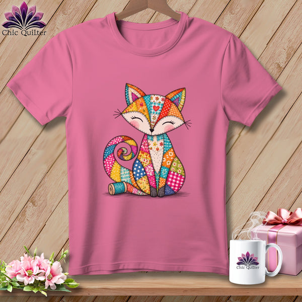 Pink t-shirt with a colorful patchwork fox graphic hanging on a wooden background.