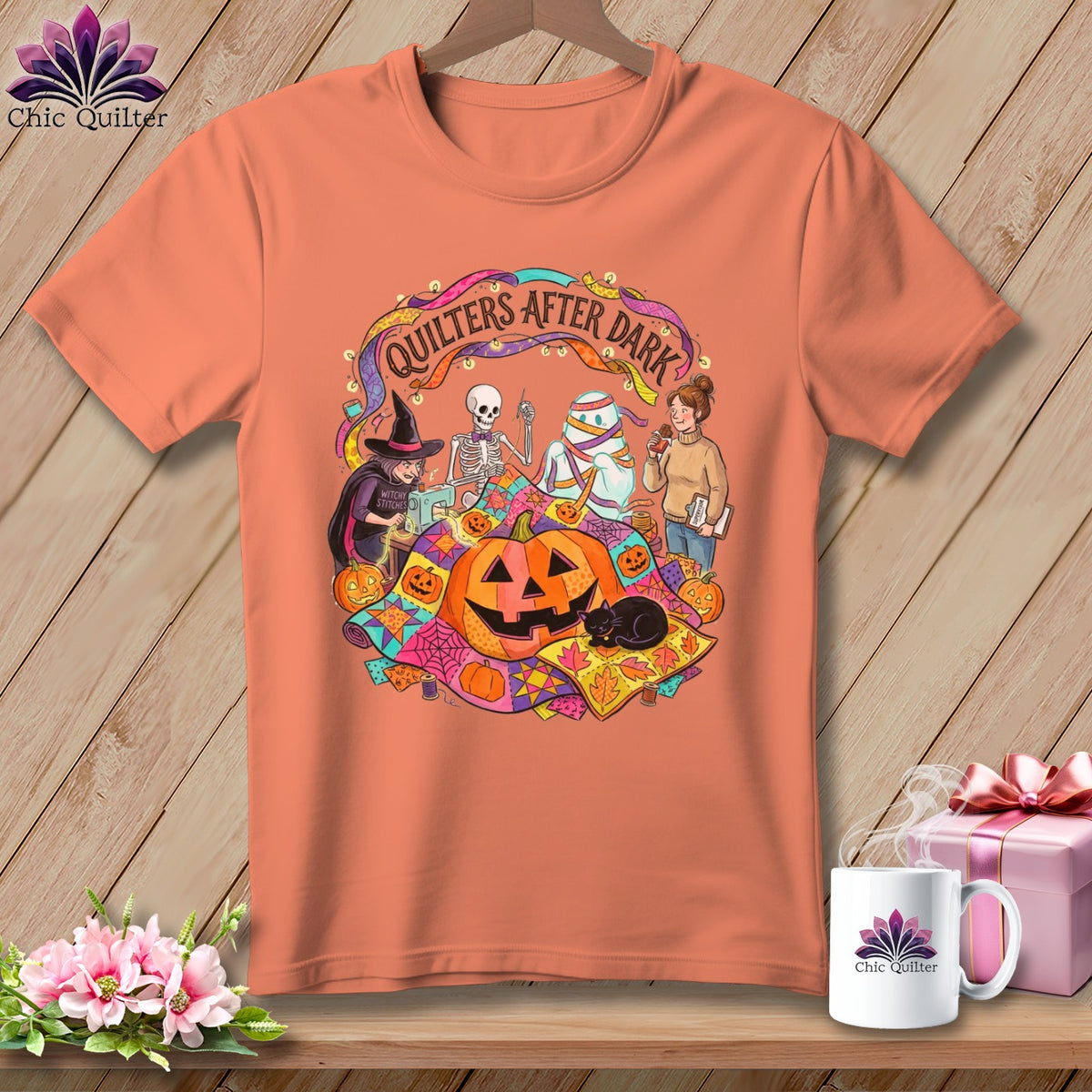 Orange t-shirt with "Quilters After Dark" Halloween graphic featuring a witch, skeleton, mummy, and pumpkins.